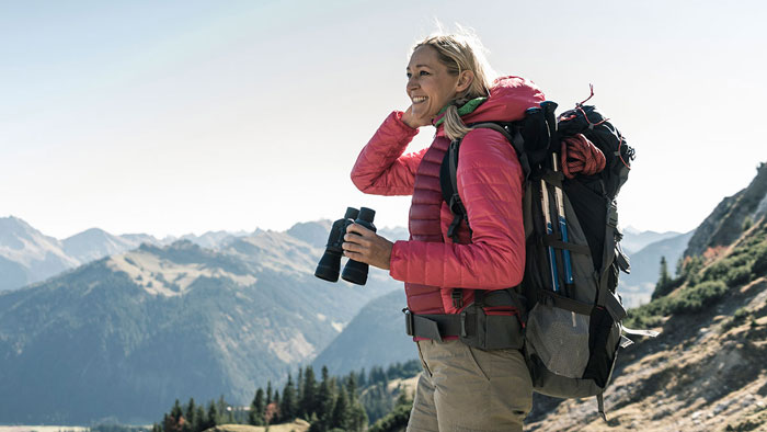 hiking woman with binoculars on mountainside