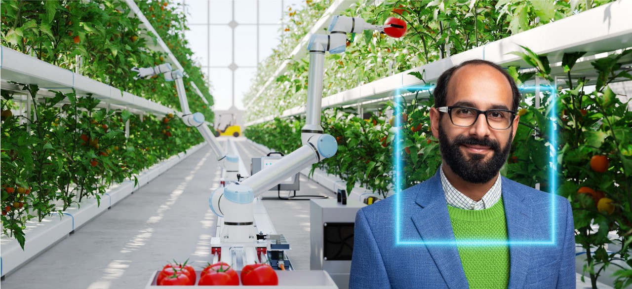 Photo of a bearded investment analyst wearing glasses and a blue jacket, with a glowing blue square around his head. He’s standing in a greenhouse with a robotic device harvesting tomatoes behind him.