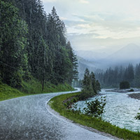 Photograph of road curving around mountains on a rainy day.