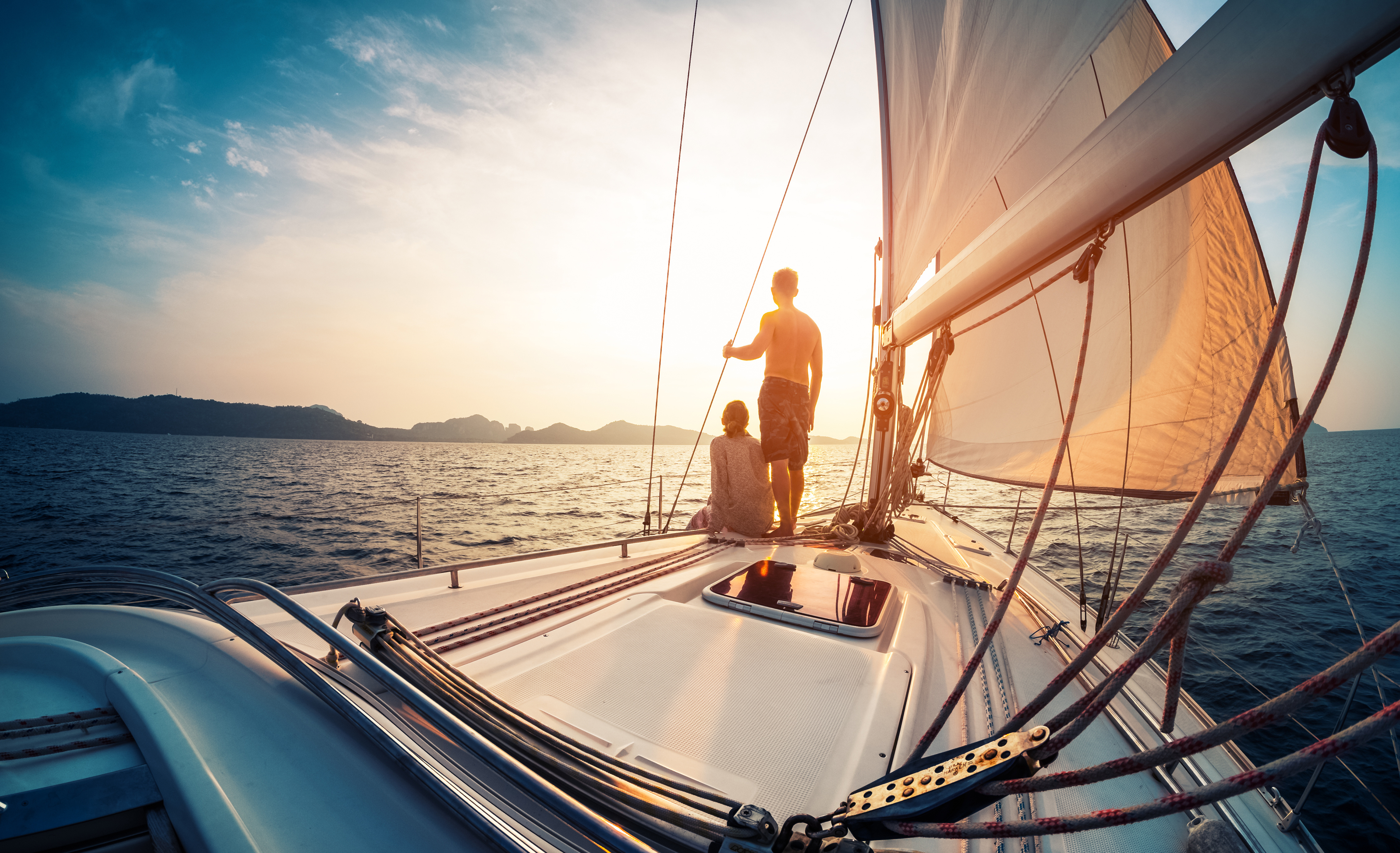 Couple enjoying sunset from the deck of the sailing boat moving in a sea