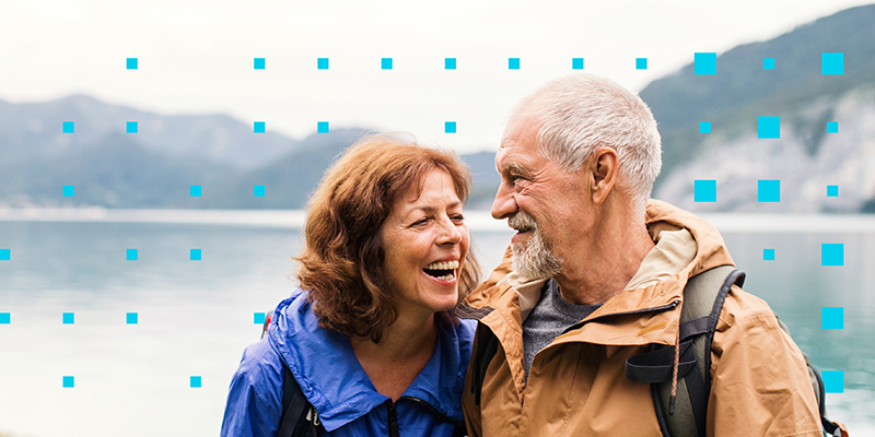 older couple side hugging and laughing on a scenic glacial hike