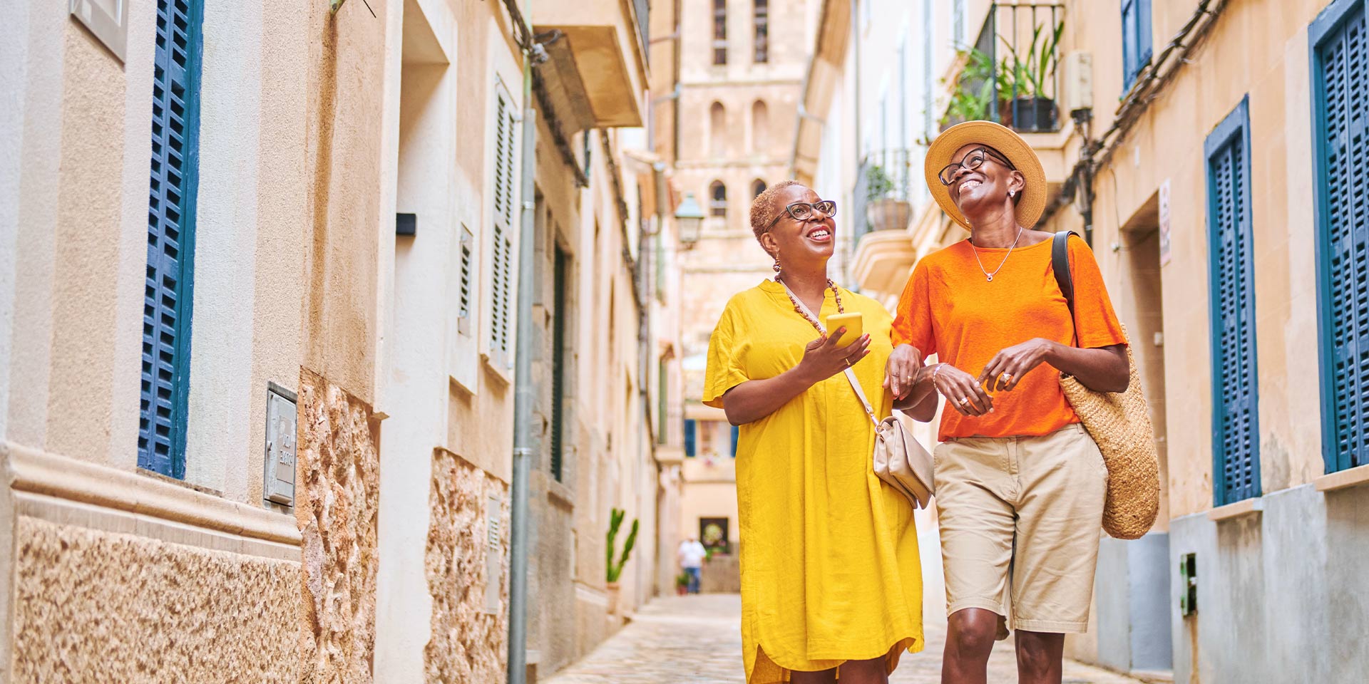 two friends walking down a cobble stone street laughing and smiling together