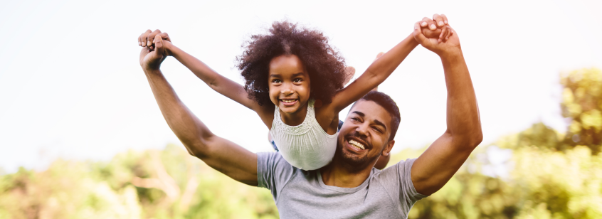 dad holding smiling daughter above his head like an airplane 