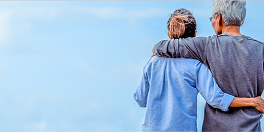 Middle aged couple looking out into the sky holding each other side by side