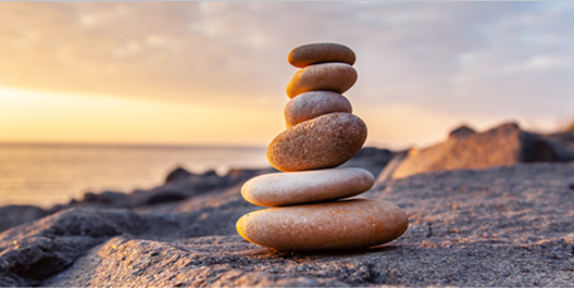 a stack of rocks balancing on a ledge in front of the ocean