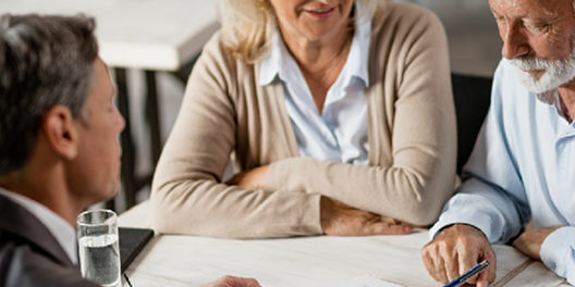 people in an office leaning over a table working and collaborating over some documents 