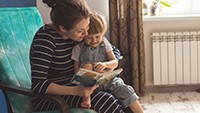 Mother reading a book to toddler in a chair