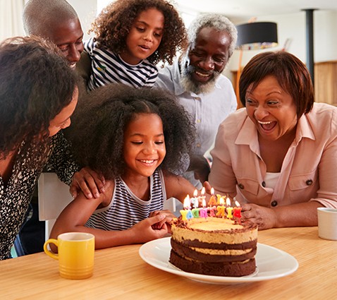 Family surrounding girl with birthday cake