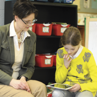 A T. Rowe Price associate helps a child learn about money management on her tablet.