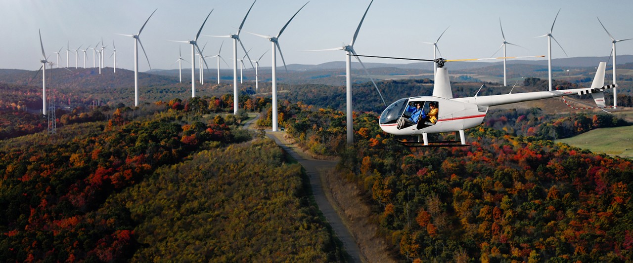 Birds-eye view of wind turbines with helicopter flying by